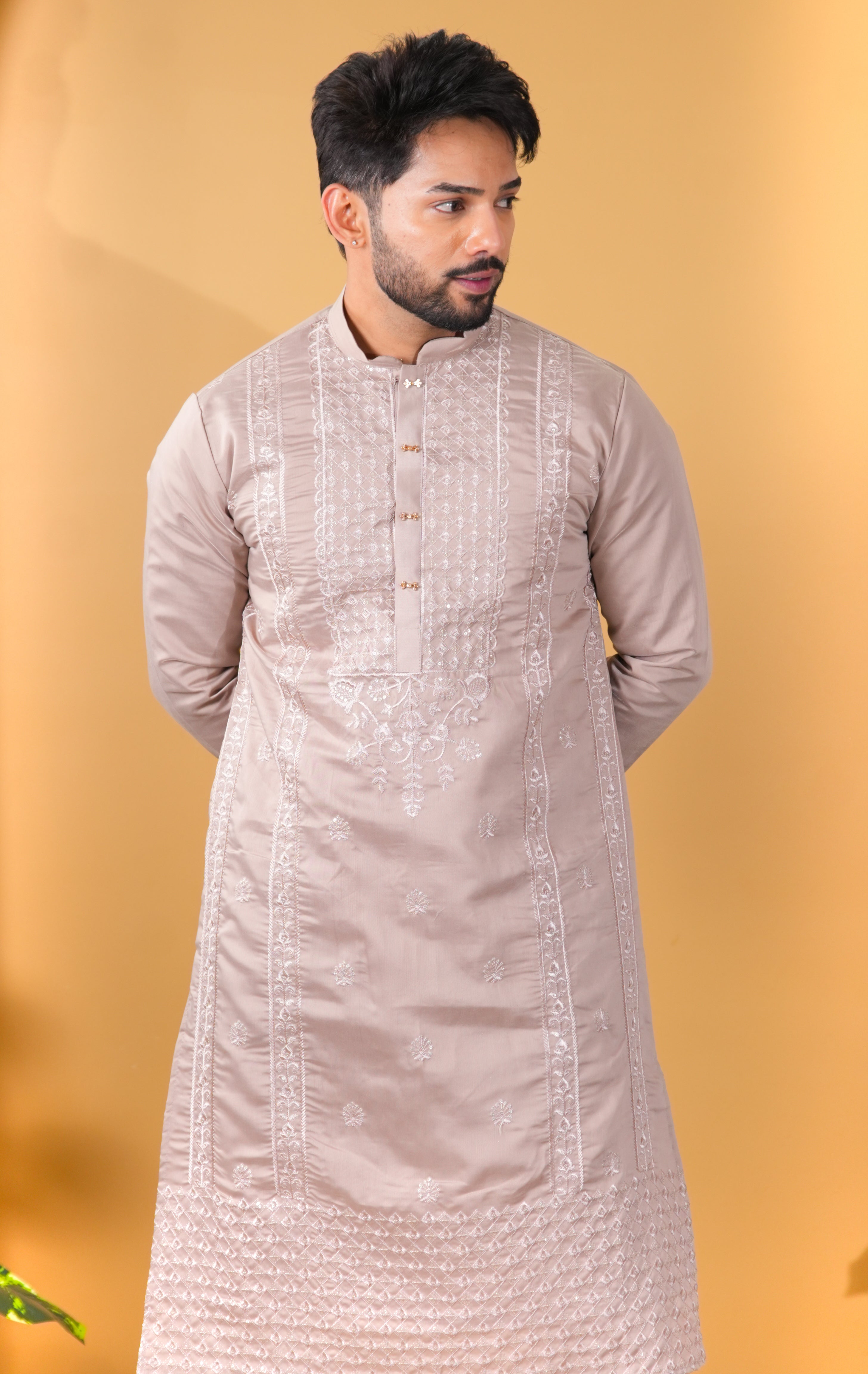 Man wearing a beige embroidered kurta against a yellow background