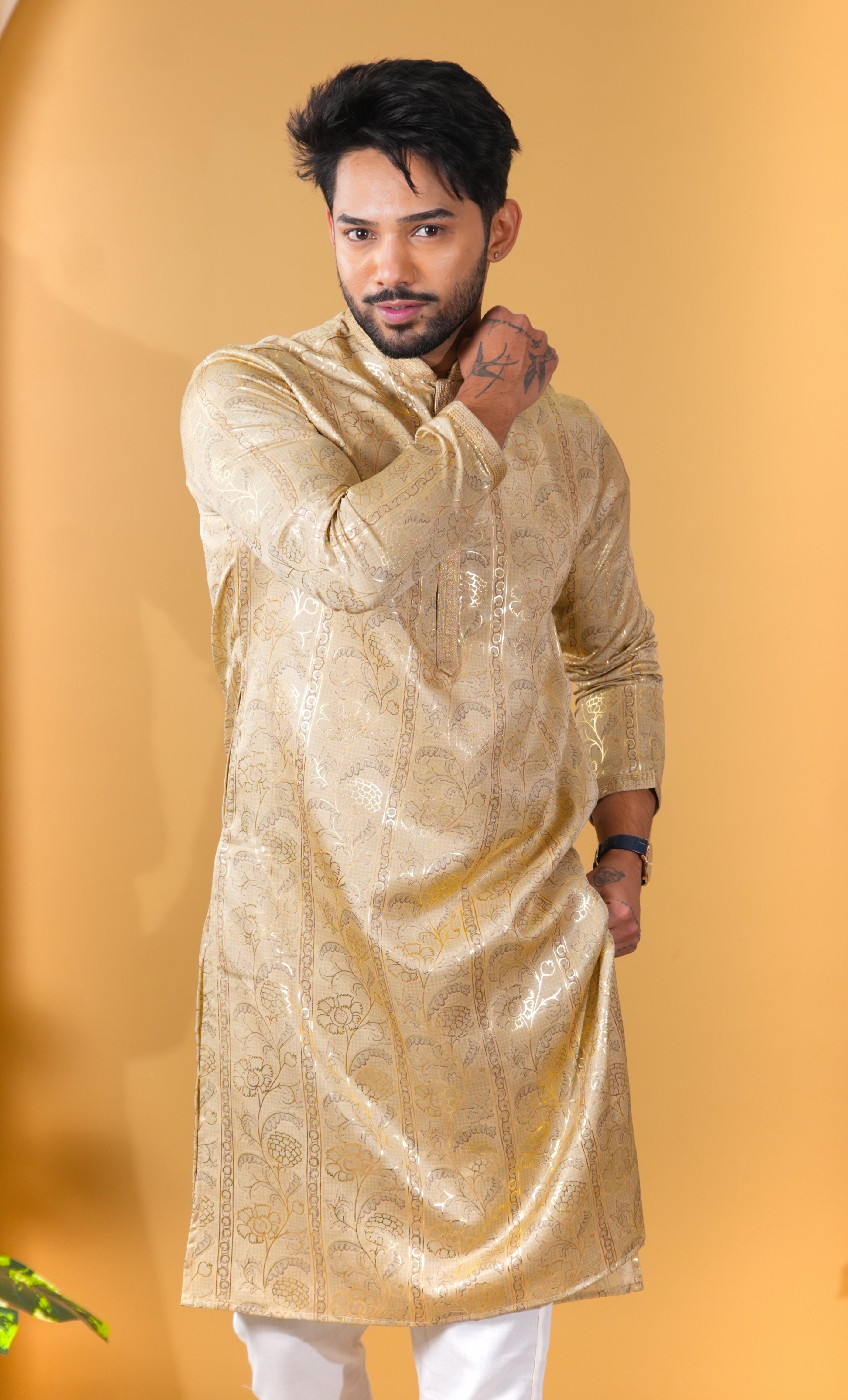Man wearing a gold kurta against a yellow background