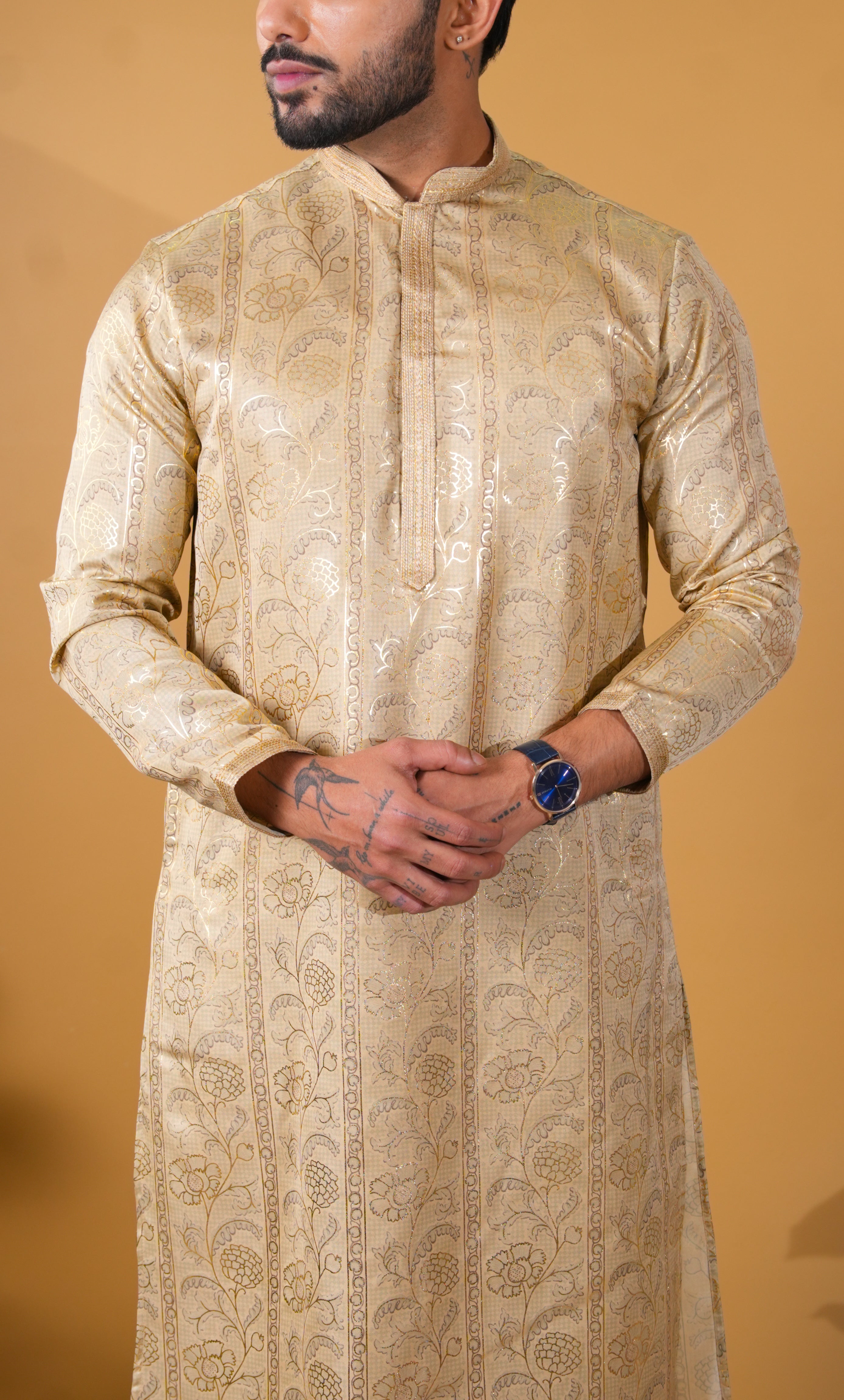 Man wearing a beige embroidered kurta against a beige background